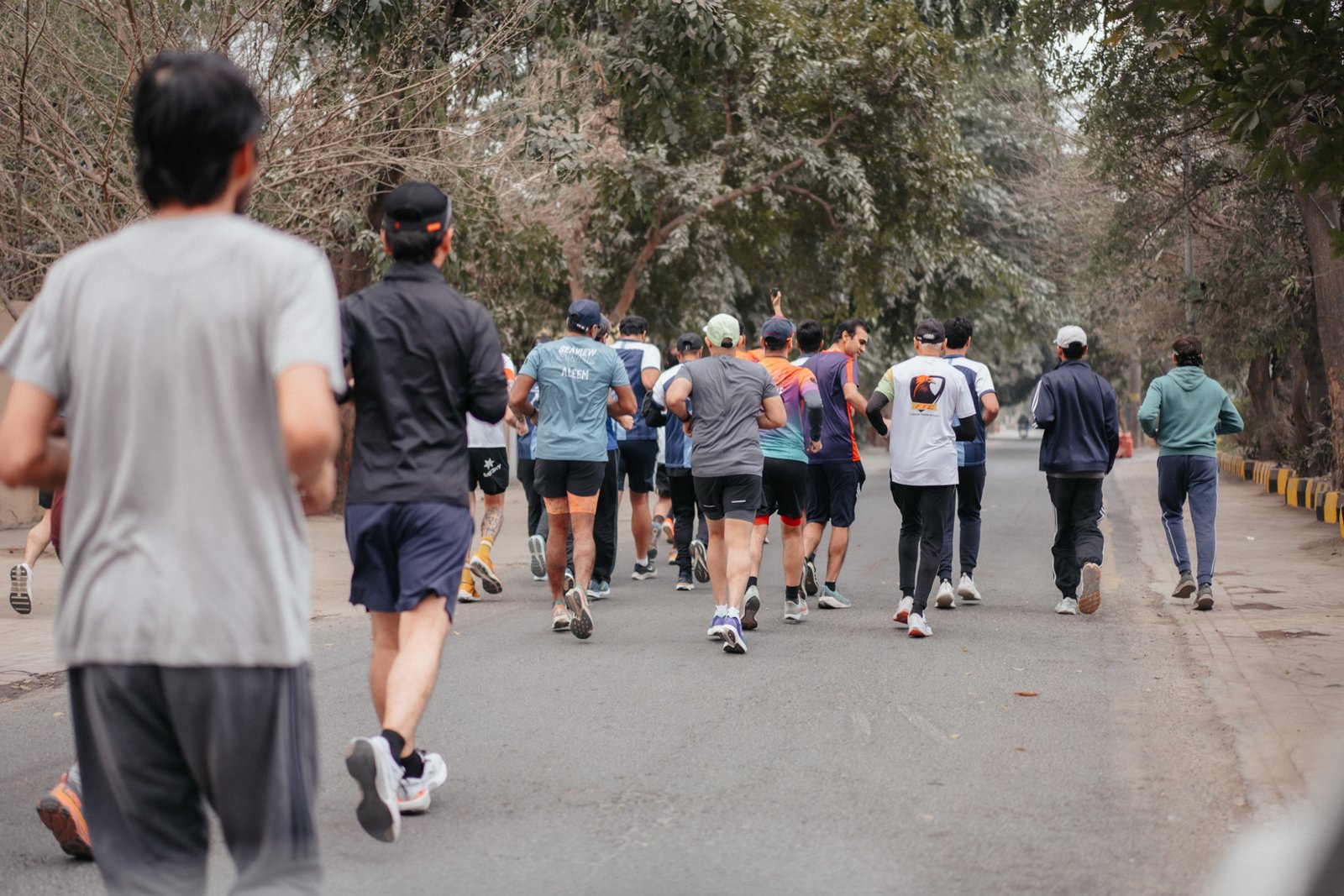 Runners strung out along a tree-lined road on the Lahore Marathon course