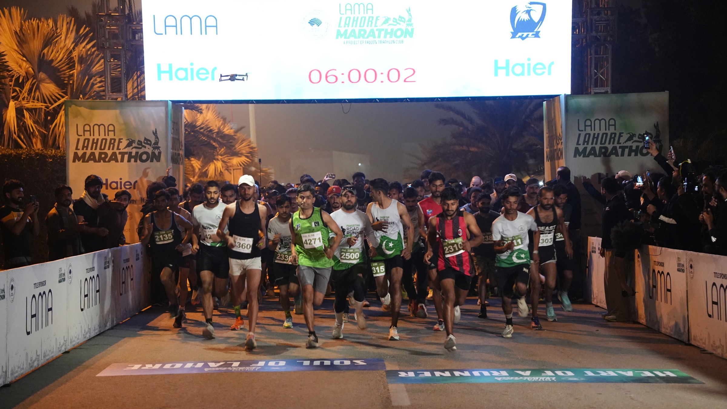 Runners packed under the Lahore Marathon start arch at dawn, moments before the start