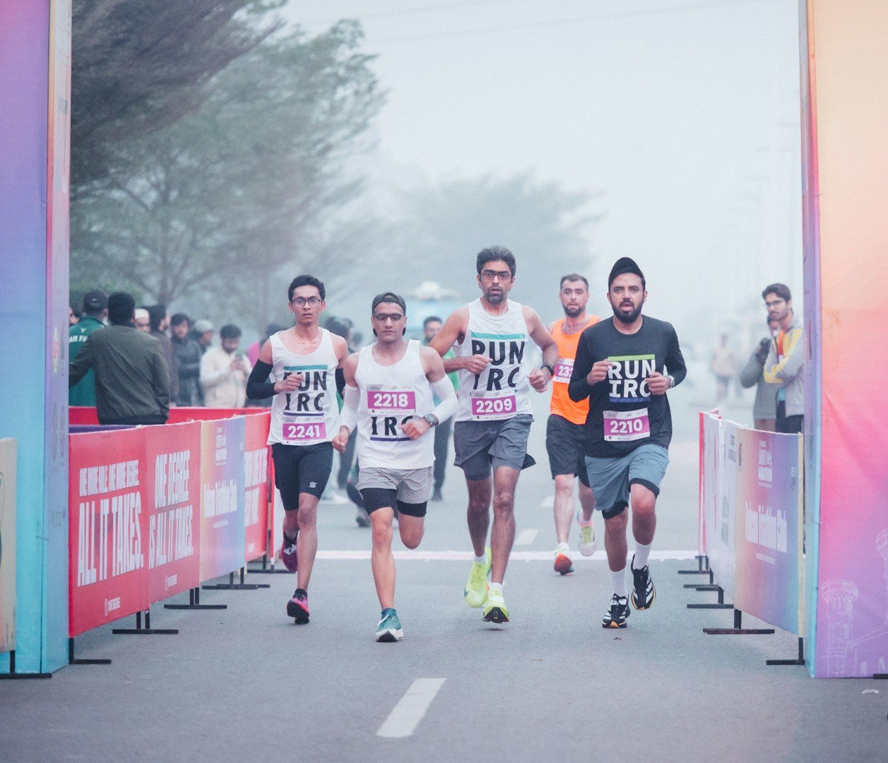 Club runners racing through the finish chute in early-morning mist