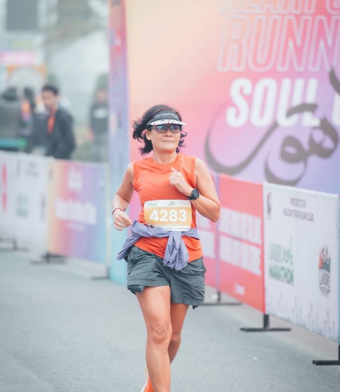 A Lahore Marathon runner racing past branded course hoardings, bib number visible