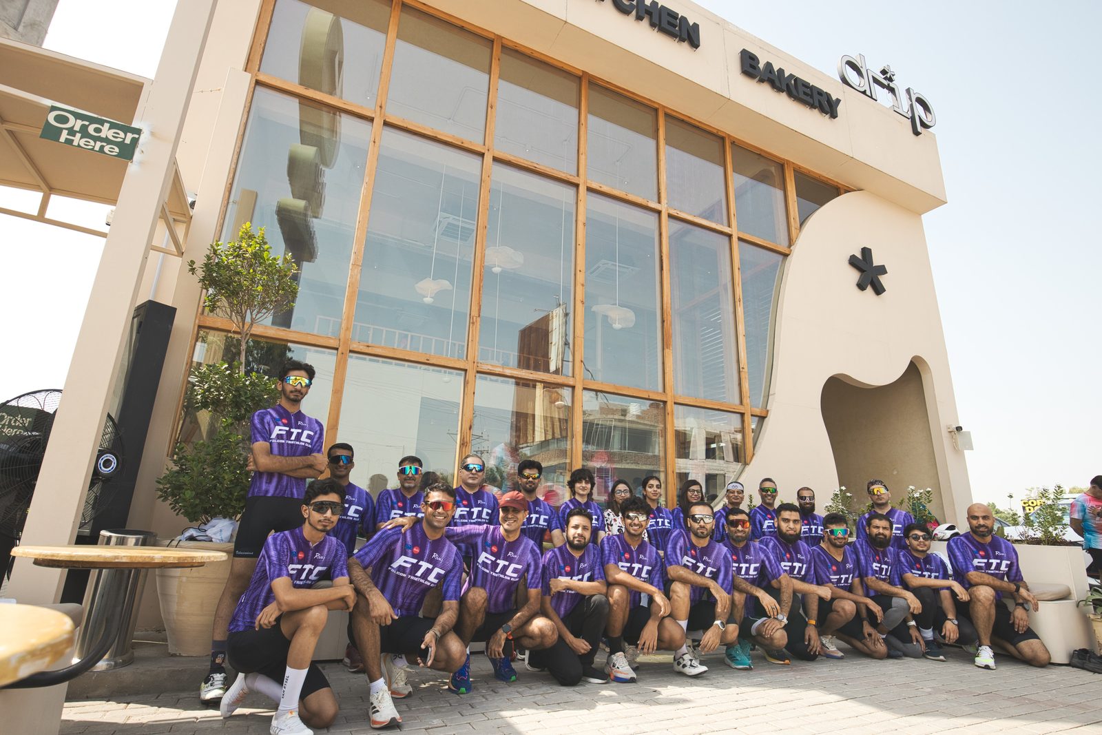 Falcon Triathlon Club members in purple club jerseys posing outside a cafe
